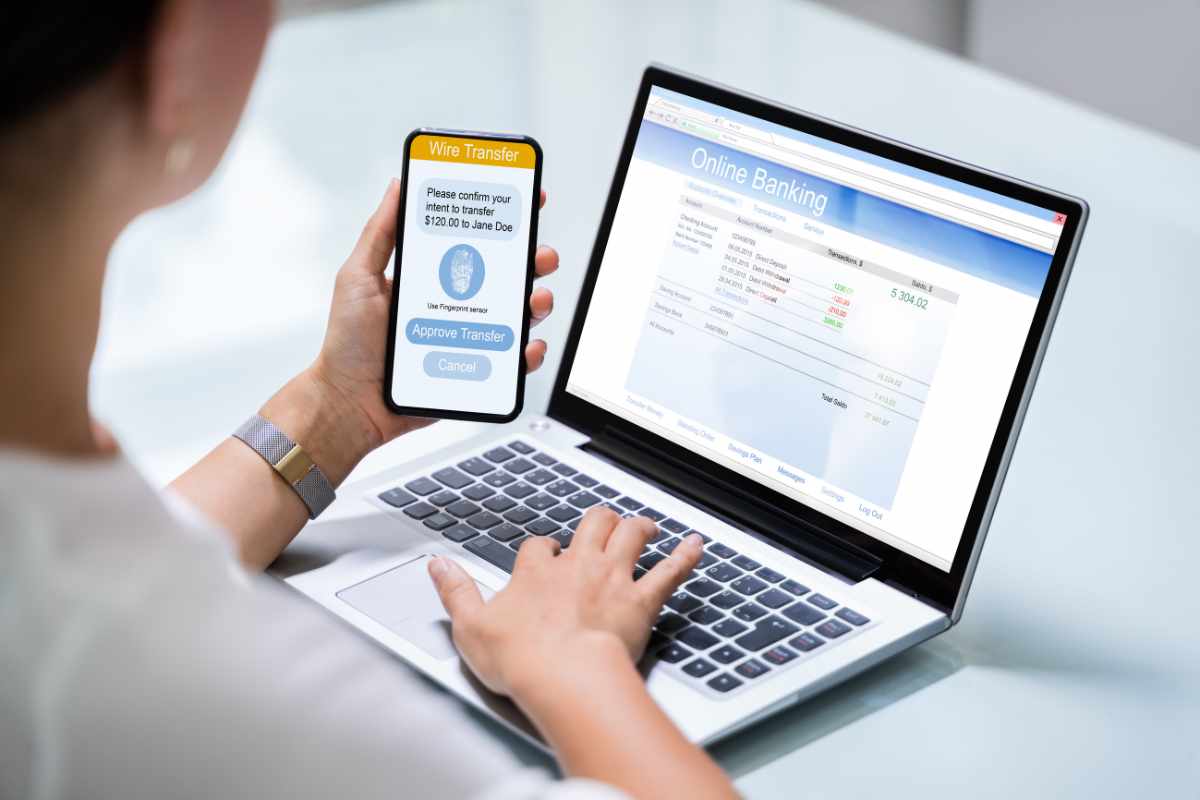 Persona al computer con il telefono in mano 