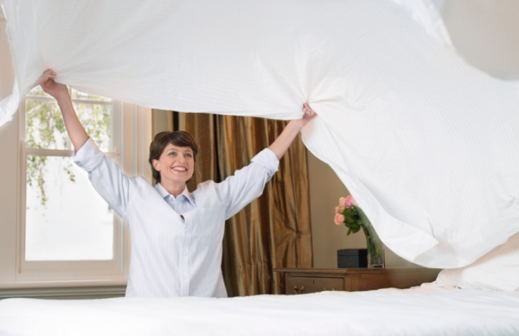 donna che cambia le lenzuola al letto