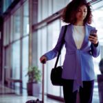 donna con trolley che guarda cellulare