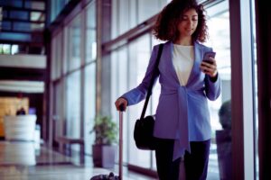 donna con trolley che guarda cellulare