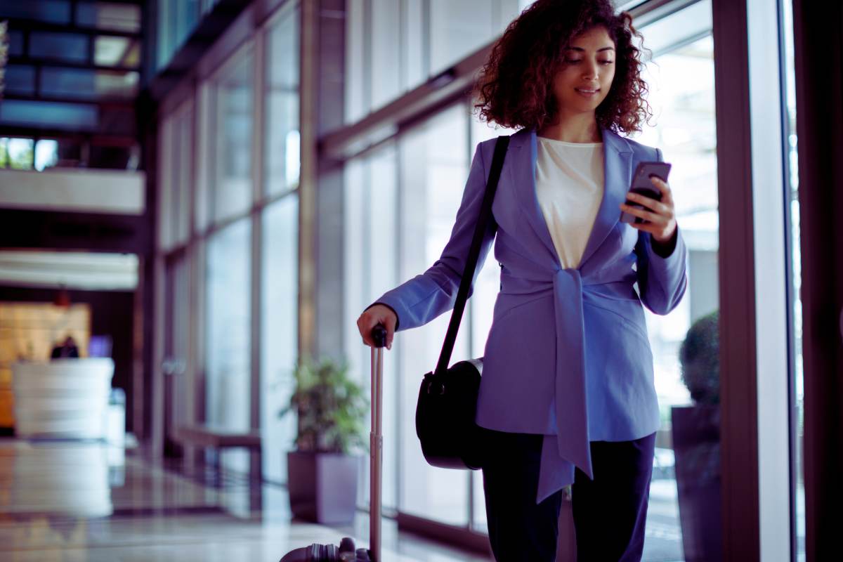 donna con trolley che guarda cellulare